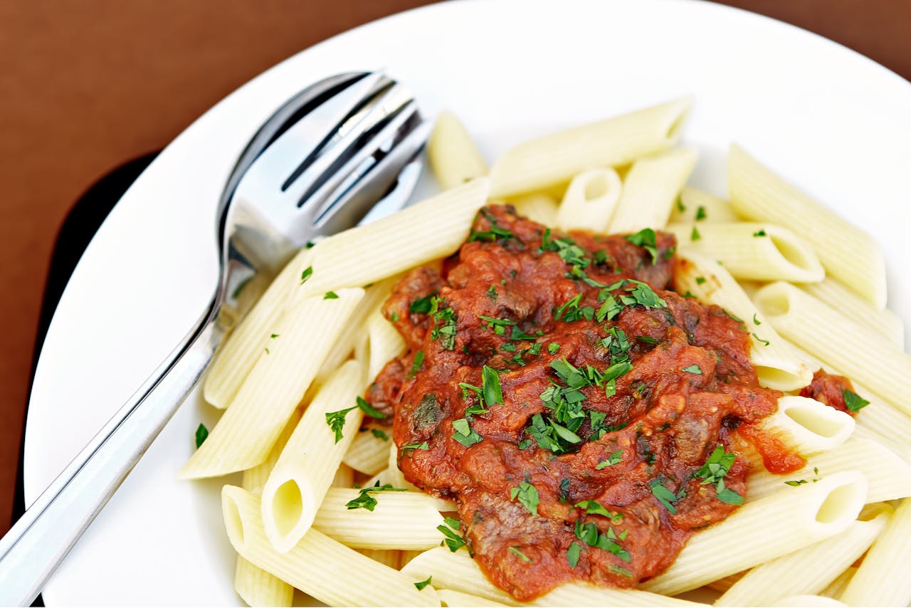 Mouthwatering penne pasta with rich tomato sauce garnished with fresh herbs.